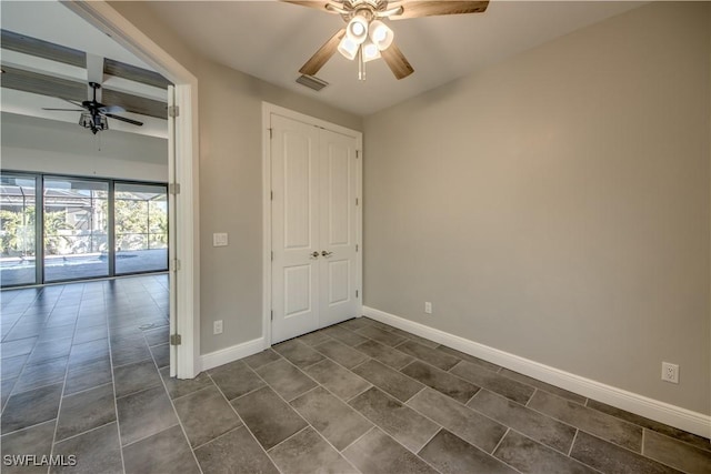 unfurnished bedroom featuring visible vents, baseboards, dark tile patterned floors, beamed ceiling, and a ceiling fan