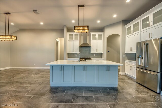 kitchen featuring white cabinets, a kitchen island with sink, pendant lighting, and high end fridge