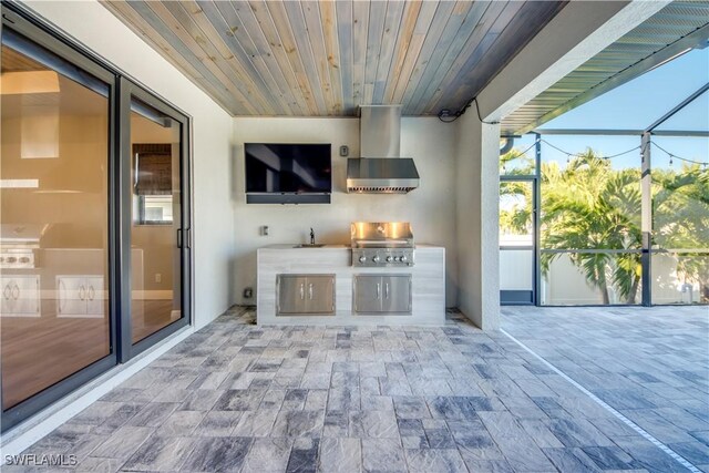 view of patio with exterior kitchen, sink, glass enclosure, and area for grilling