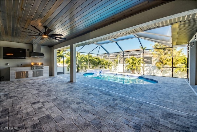 view of patio with a pool with connected hot tub, an outdoor kitchen, glass enclosure, a grill, and ceiling fan