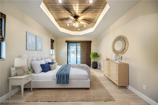 bedroom with a raised ceiling, light wood-style flooring, wooden ceiling, baseboards, and ceiling fan