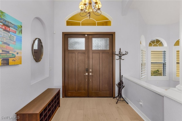 entryway with light hardwood / wood-style floors, a high ceiling, and a notable chandelier