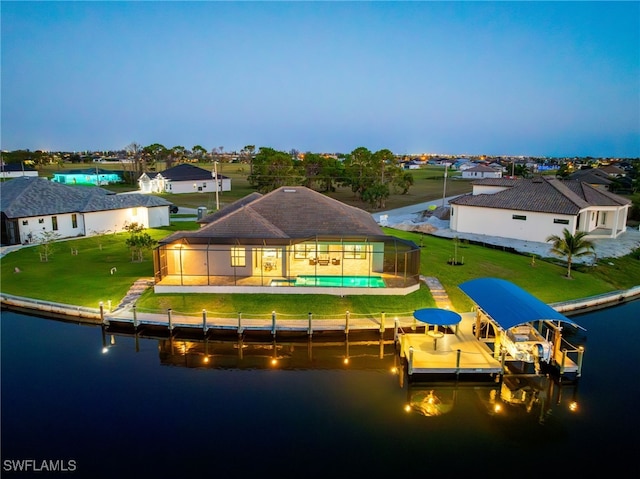 back house at dusk featuring a pool, a yard, a water view, and glass enclosure