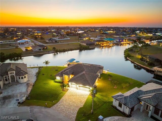 aerial view at dusk featuring a water view