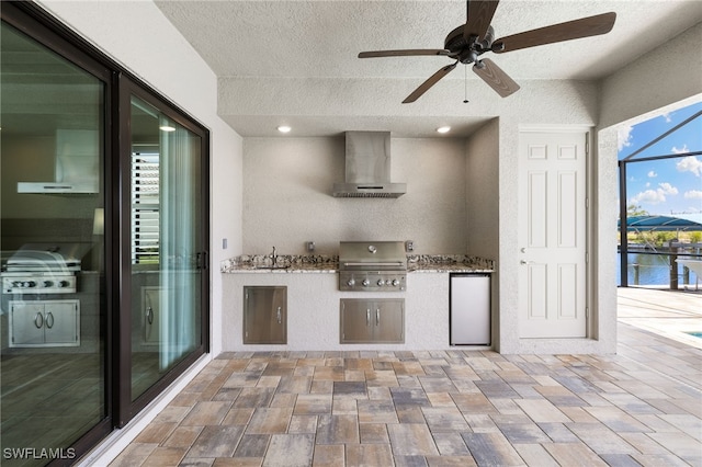 kitchen with sink, fridge, a water view, a textured ceiling, and wall chimney exhaust hood