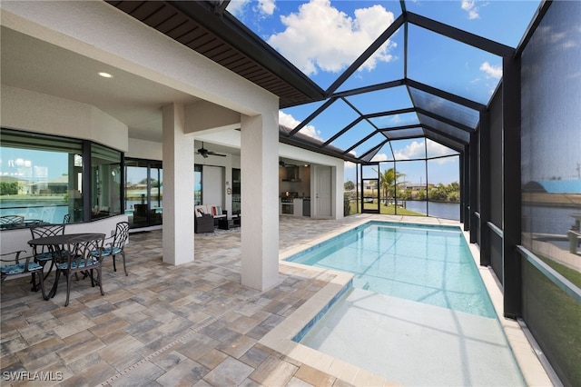 view of pool with a patio area, a water view, and exterior kitchen