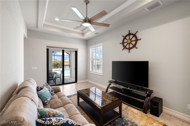 living room with ceiling fan, a raised ceiling, and light tile patterned floors