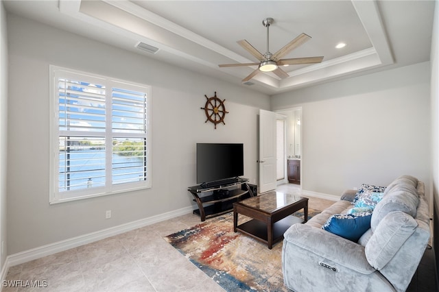 living room featuring a raised ceiling, ornamental molding, tile patterned flooring, and ceiling fan