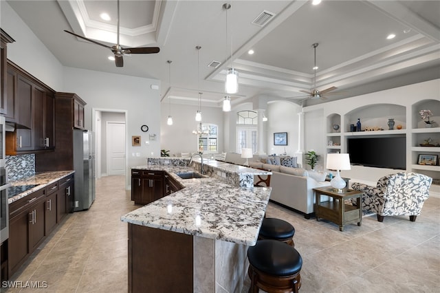 kitchen featuring decorative light fixtures, sink, ceiling fan, and a tray ceiling