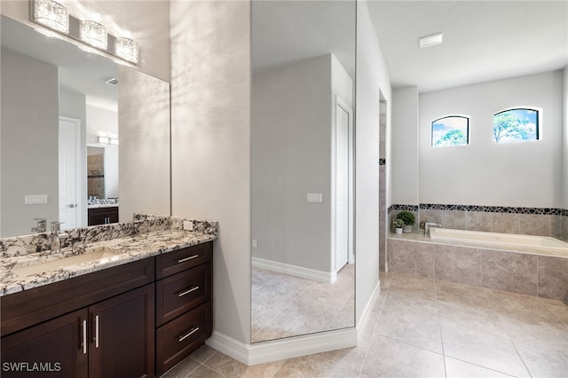 bathroom with vanity, tile patterned flooring, and tiled bath