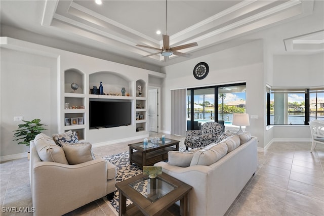 tiled living room with crown molding, built in features, ceiling fan, and a tray ceiling