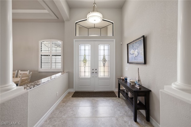 foyer entrance with decorative columns, light tile patterned floors, and french doors