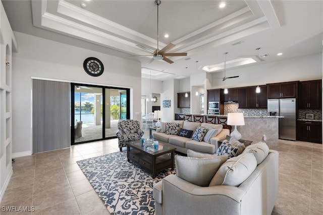 tiled living room featuring ceiling fan, ornamental molding, a raised ceiling, and a towering ceiling