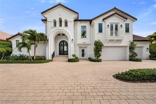 mediterranean / spanish house featuring french doors, a balcony, and a garage