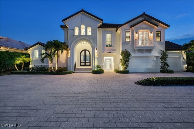 mediterranean / spanish home with french doors, a balcony, and a garage