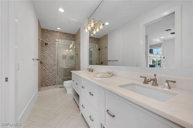 bathroom featuring toilet, vanity, tile patterned flooring, tiled shower, and an inviting chandelier