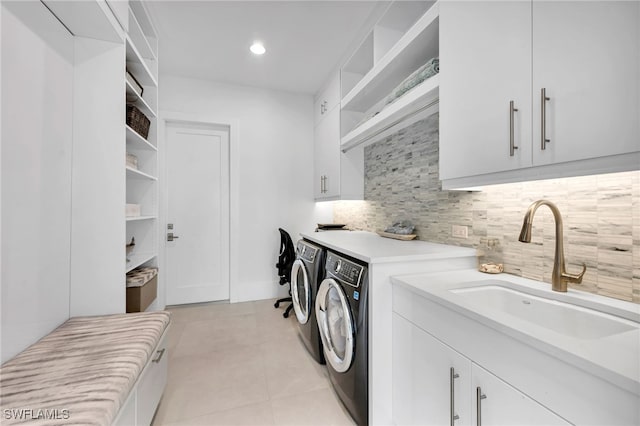 laundry room with light tile patterned floors, sink, separate washer and dryer, and cabinets