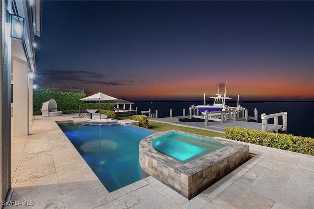 pool at dusk featuring a patio area, a water view, an in ground hot tub, and a dock