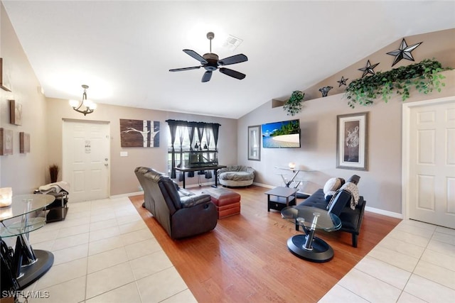 living room with tile patterned floors, visible vents, ceiling fan, and vaulted ceiling