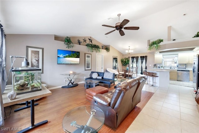 living room featuring light tile patterned floors, ceiling fan with notable chandelier, baseboards, and vaulted ceiling