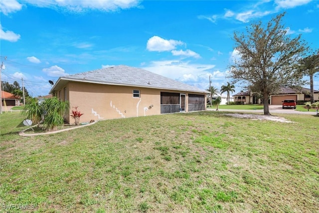 back of house with stucco siding, a yard, and a sunroom