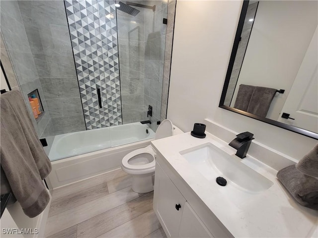 full bathroom featuring wood-type flooring, combined bath / shower with glass door, vanity, and toilet