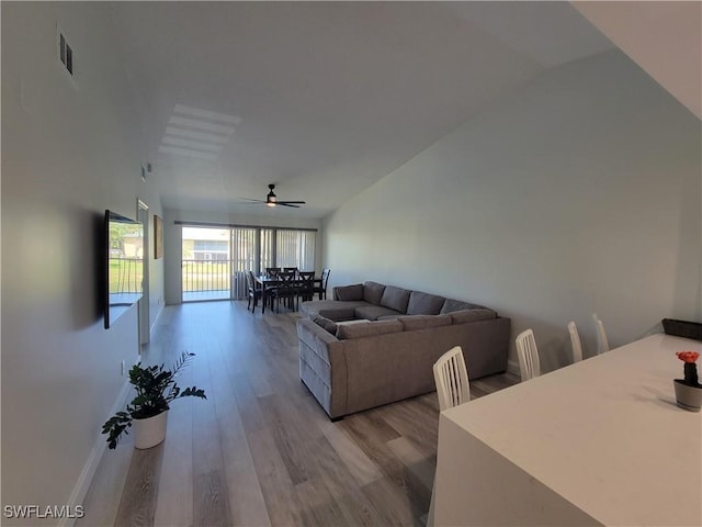 living room with ceiling fan, lofted ceiling, and light hardwood / wood-style flooring