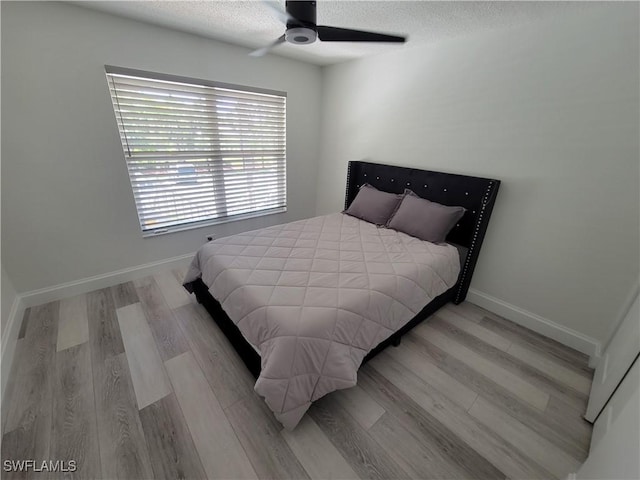 bedroom with a textured ceiling, ceiling fan, and light hardwood / wood-style flooring