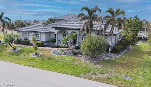 view of front facade featuring stucco siding, a front lawn, and a tiled roof