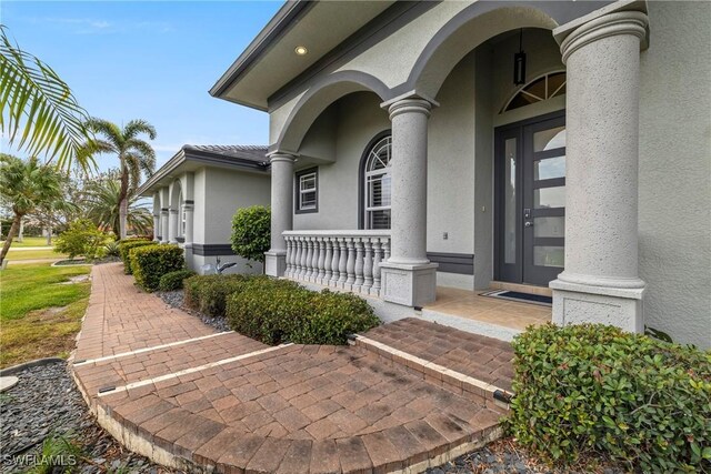 view of exterior entry featuring covered porch and stucco siding