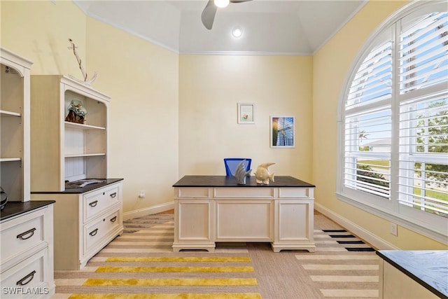 office area with vaulted ceiling, crown molding, baseboards, and a ceiling fan