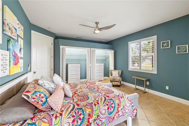 bedroom with ceiling fan, light tile patterned floors, and two closets