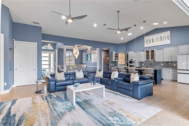 living room with visible vents, high vaulted ceiling, ceiling fan with notable chandelier, arched walkways, and light tile patterned flooring