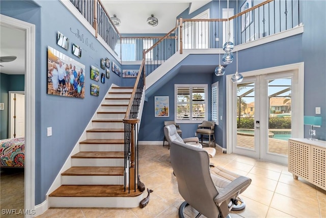 stairs with tile patterned flooring, a towering ceiling, baseboards, and a ceiling fan