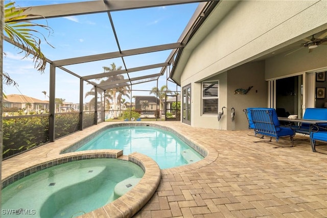 view of swimming pool with a pool with connected hot tub, a patio area, a ceiling fan, and glass enclosure