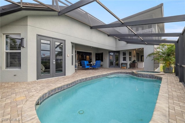 exterior space featuring a pool with connected hot tub, a patio area, a lanai, and french doors