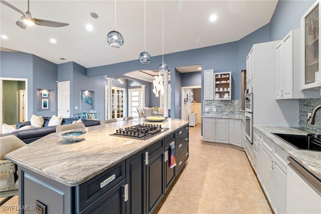 kitchen featuring white cabinets, stainless steel appliances, decorative columns, and a sink