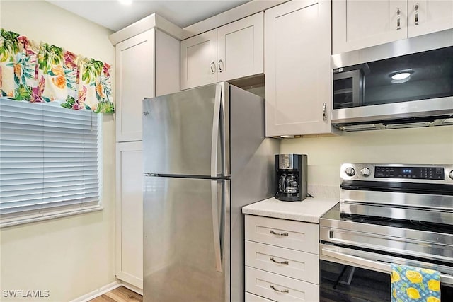 2888 Oleander St Unit C6, Saint James City, FL 33956 - kitchen with white cabinets, stainless steel appliances, and light wood-type flooring