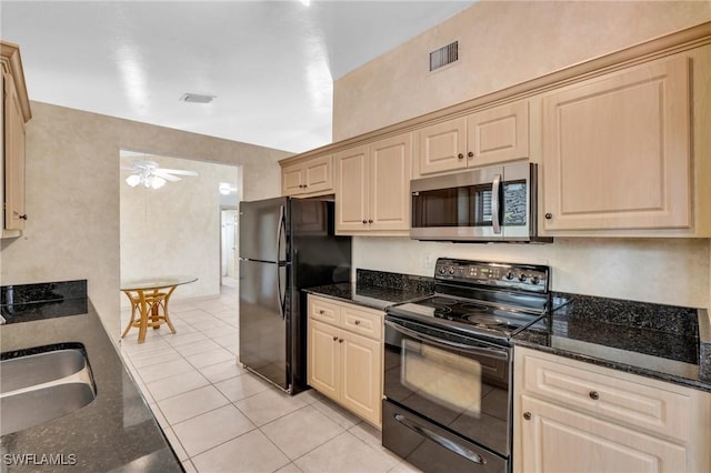 kitchen featuring black appliances, dark stone counters, sink, ceiling fan, and light tile patterned floors