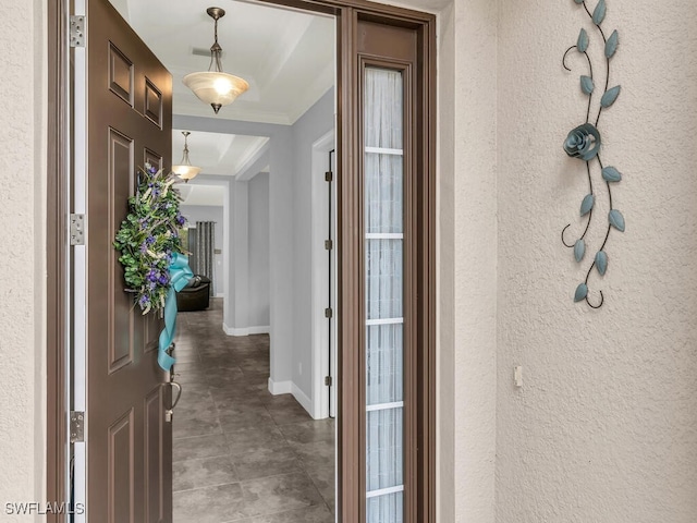 foyer entrance featuring crown molding, baseboards, and a textured wall