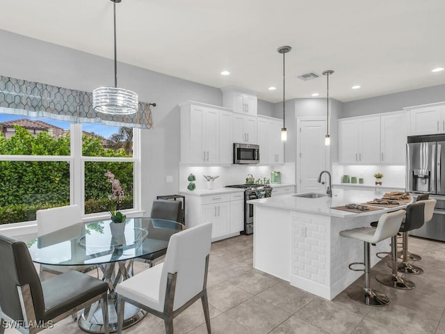 kitchen with decorative backsplash, a sink, visible vents, stainless steel appliances, and light countertops