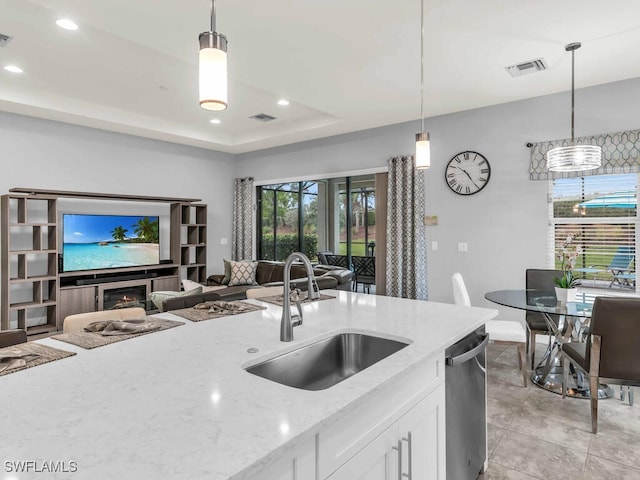 kitchen with visible vents, a sink, open floor plan, a tray ceiling, and stainless steel dishwasher