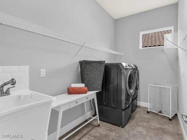 laundry room with laundry area, washing machine and dryer, baseboards, and a sink