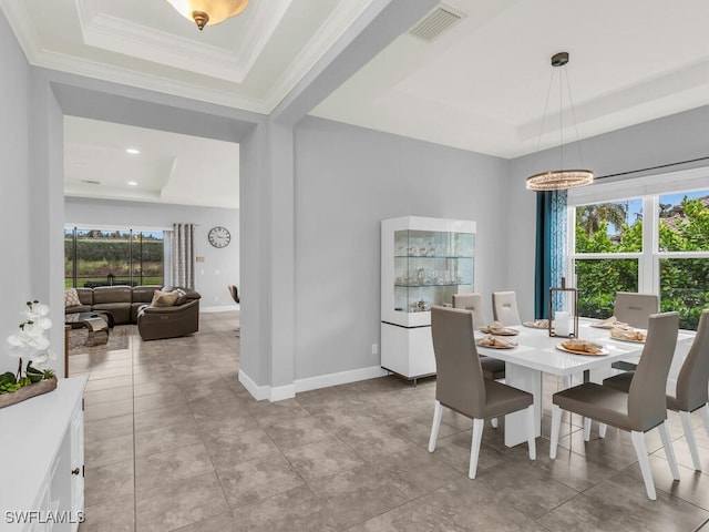 dining space with light tile patterned floors, ornamental molding, baseboards, visible vents, and a raised ceiling