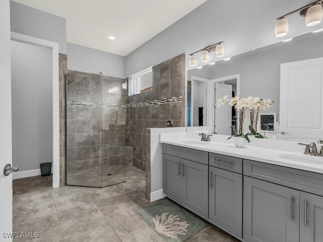 full bathroom with baseboards, a walk in shower, double vanity, and a sink