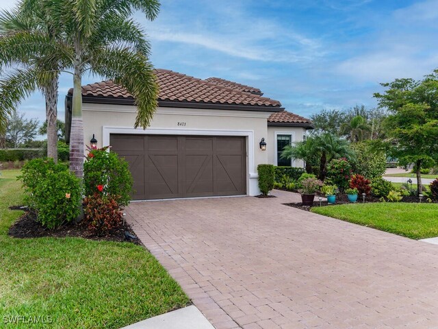 mediterranean / spanish-style home featuring a front yard and a garage