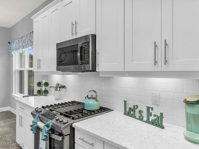 kitchen with decorative backsplash, light stone countertops, appliances with stainless steel finishes, and white cabinets