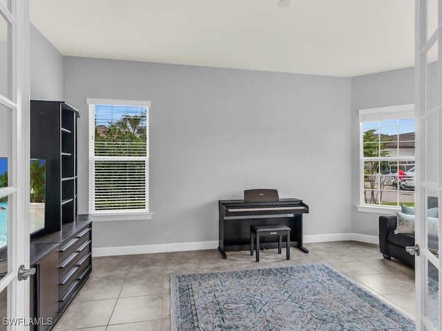 living area with tile patterned floors, french doors, and baseboards