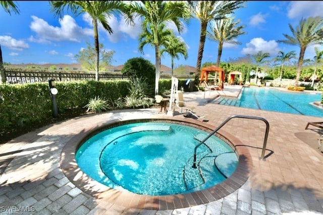 community pool with a patio area, a community hot tub, and fence