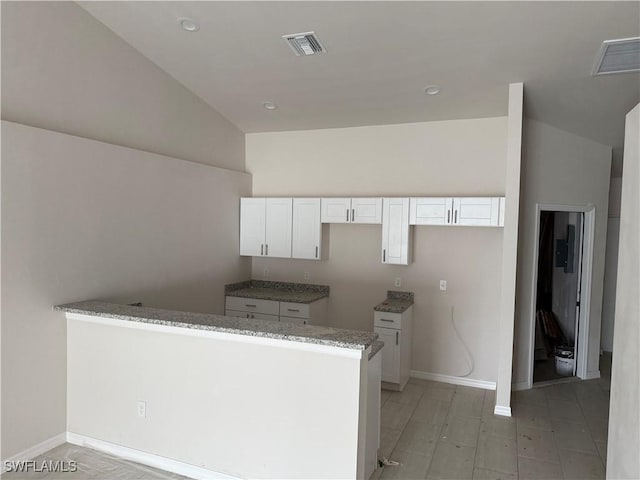 kitchen with high vaulted ceiling, white cabinetry, kitchen peninsula, and light stone countertops